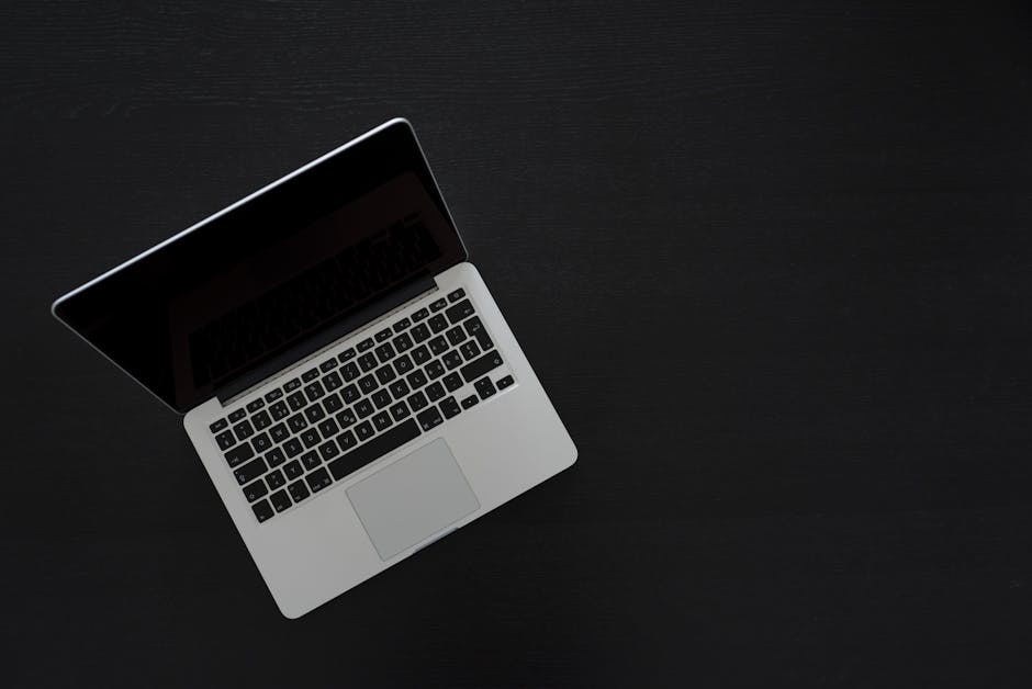 Overhead view of a MacBook laptop on a dark desk, showcasing modern technology and minimalism.